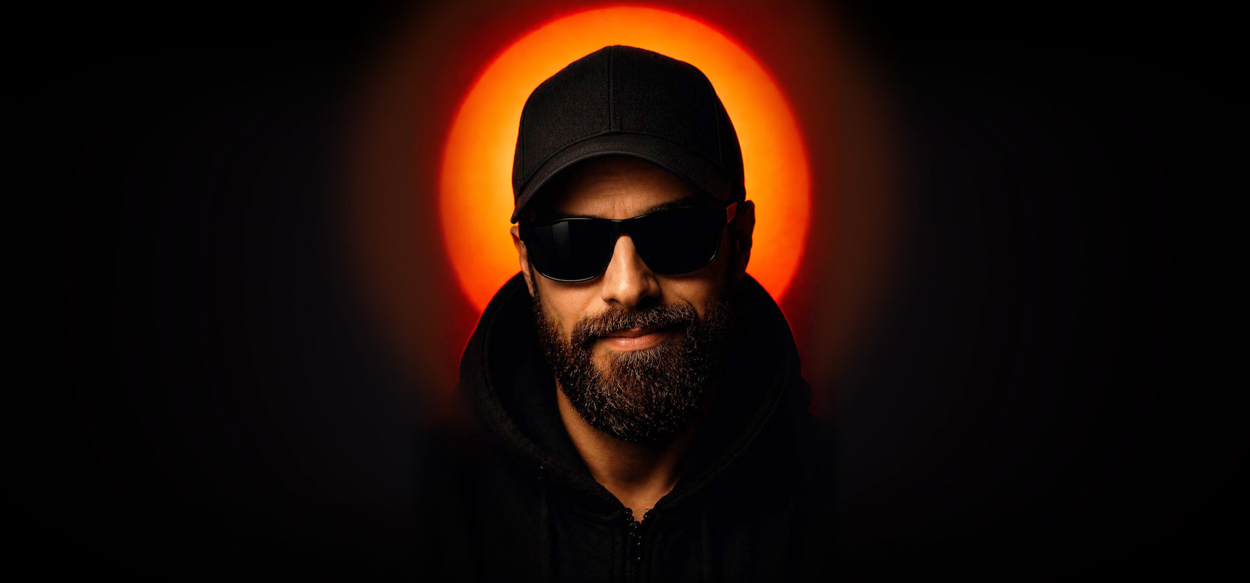 Todor Andonov wearing a black cap and sunglasses against an orange light